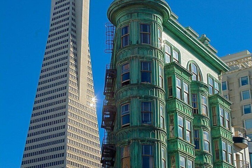 A tall modern building and a historic building with green trim and ornate details. 2