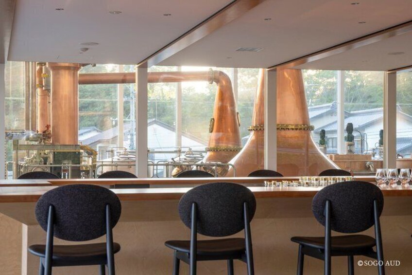 A bar area with large windows, copper distillation columns, and modern chairs. 2