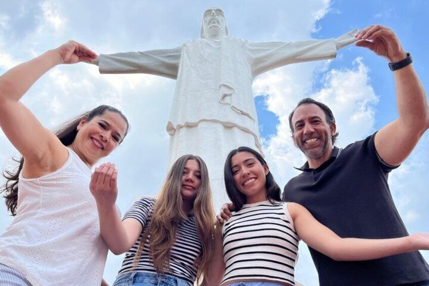 A group of people posing in front of a large statue. 1