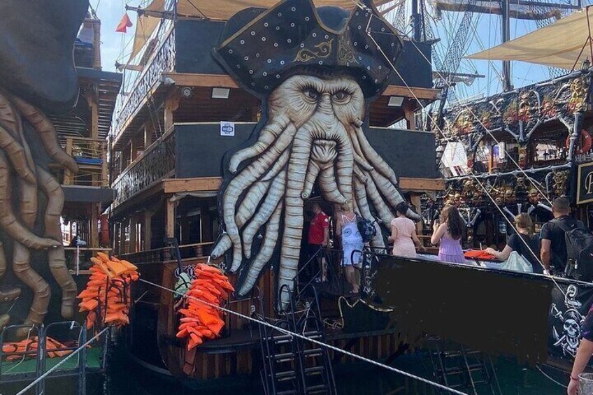 A large octopus sculpture on a boat, surrounded by people and various items. 1