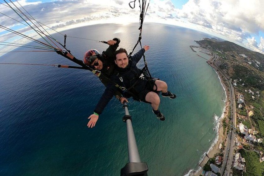 Two people skydiving over a coastal area with a clear view of the ocean and a coastline. 3