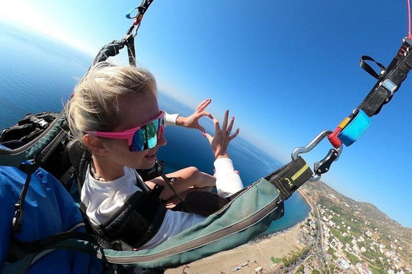 A person in a harness with a parachute, overlooking a coastal landscape. 4