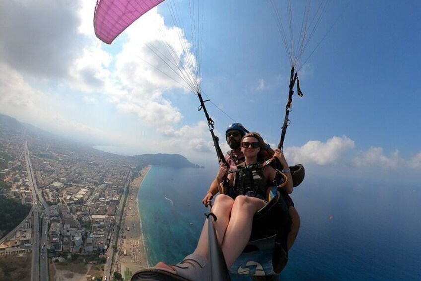 A person paragliding over a coastal city with a clear view of the coastline and a bridge. 5