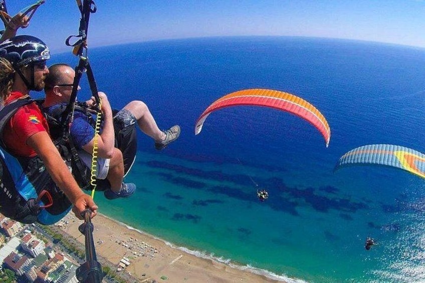 Paragliders over a beach with clear turquoise waters. 2