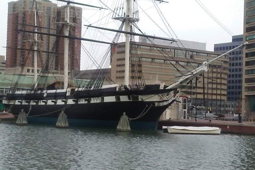 A tall ship docked in a harbor with buildings in the background. 1
