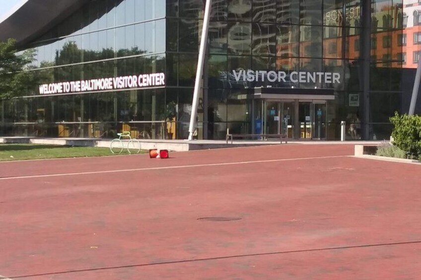 A modern building with a sign reading 'VISITOR CENTER' and a red paved area in front. 5