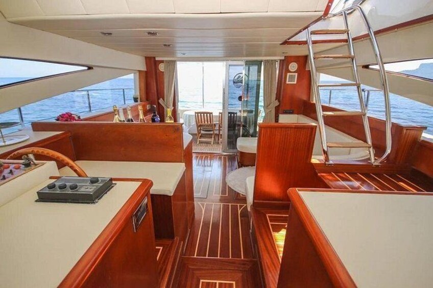 A yacht's interior with wooden furniture, a steering wheel, and a view of the sea. 5