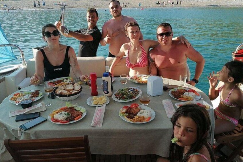 A group of people dining on a boat with various dishes on the table. 2