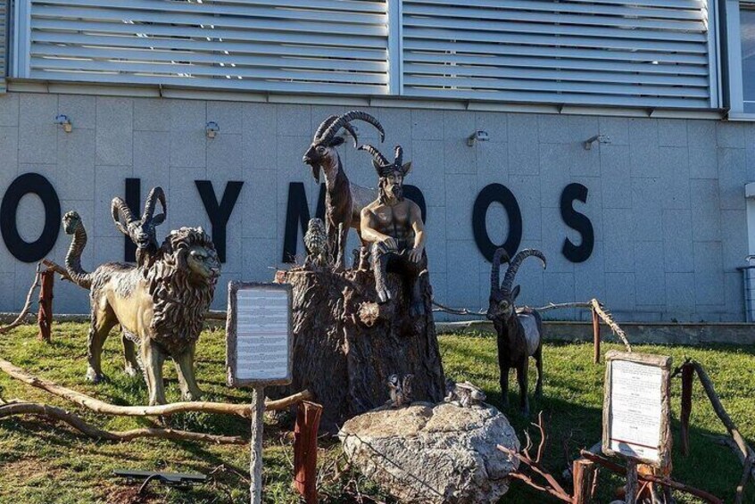 A sculpture of animals in front of a building with 'OLYMPIOS' on the wall. 5