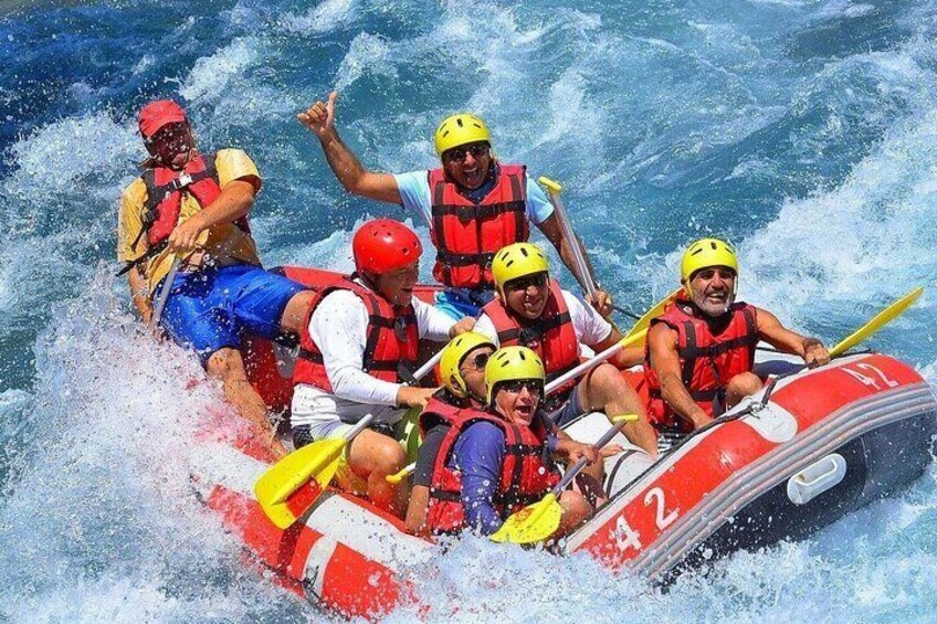 A group of people in a red inflatable raft navigating through rough waters. 1