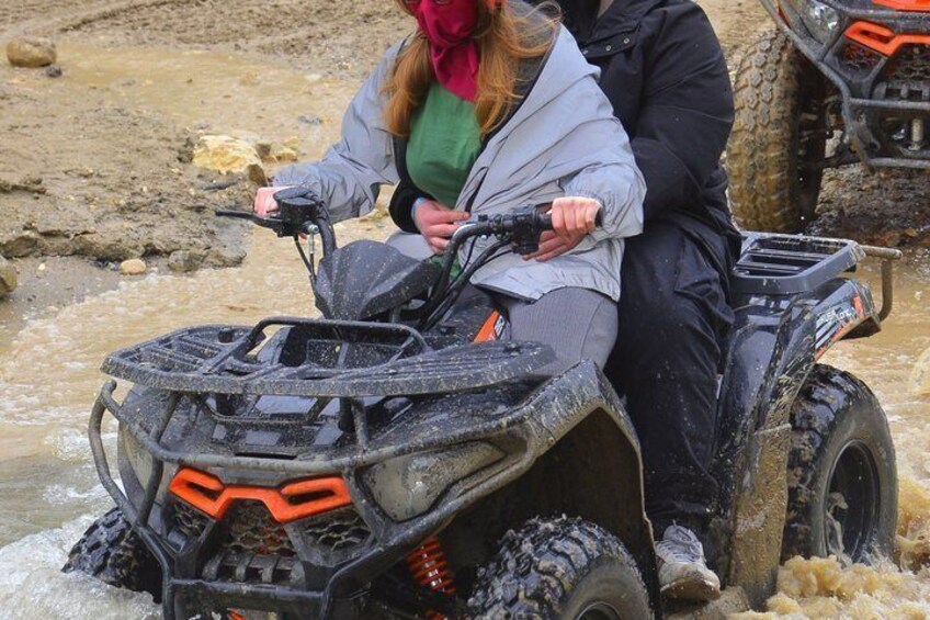 A person riding an ATV through a muddy area. 2