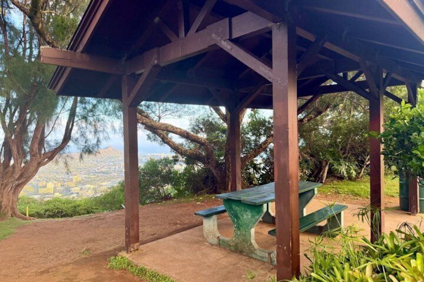 A covered picnic area with benches and a view of a city in the distance. 3