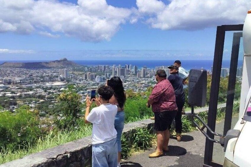 A group of people taking photos of a cityscape with a mountain in the background. 2
