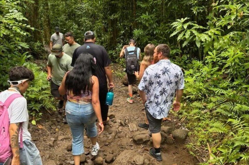 A group of people hiking through a dense forest with muddy terrain. 5