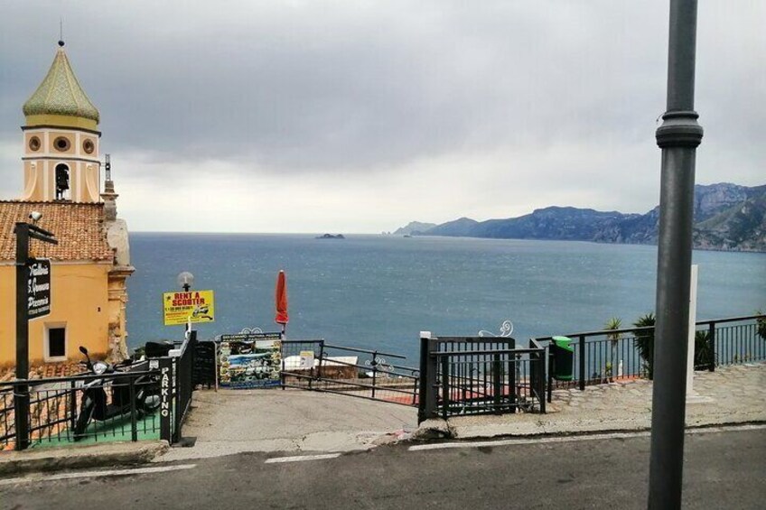 A coastal view with a church, a signboard, and a railing overlooking the sea. 3