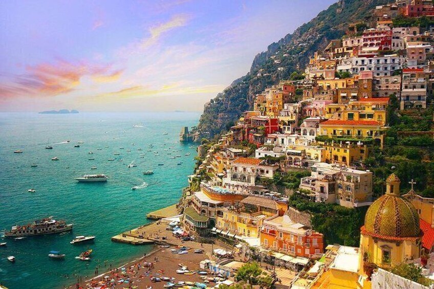 A coastal town with colorful buildings, a beach, and boats on the water. 5