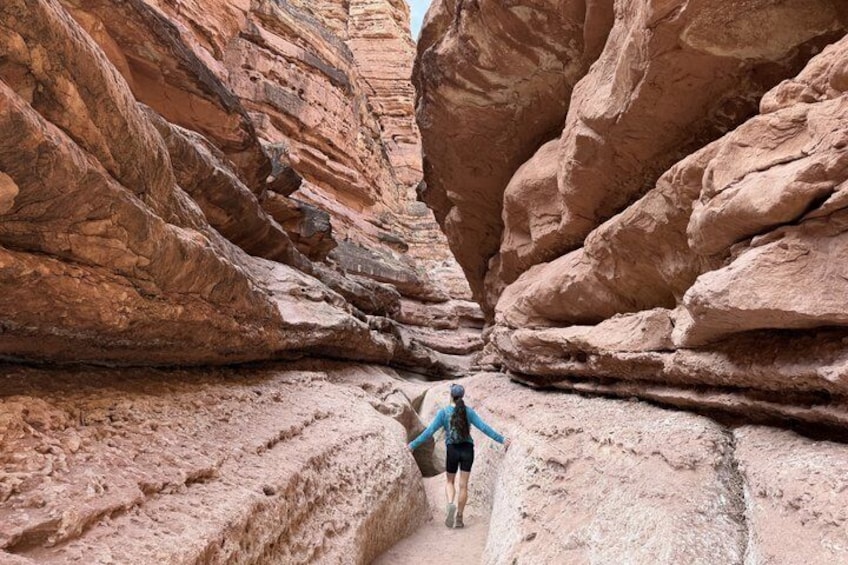 A person hiking through a narrow canyon with red rock walls. 1