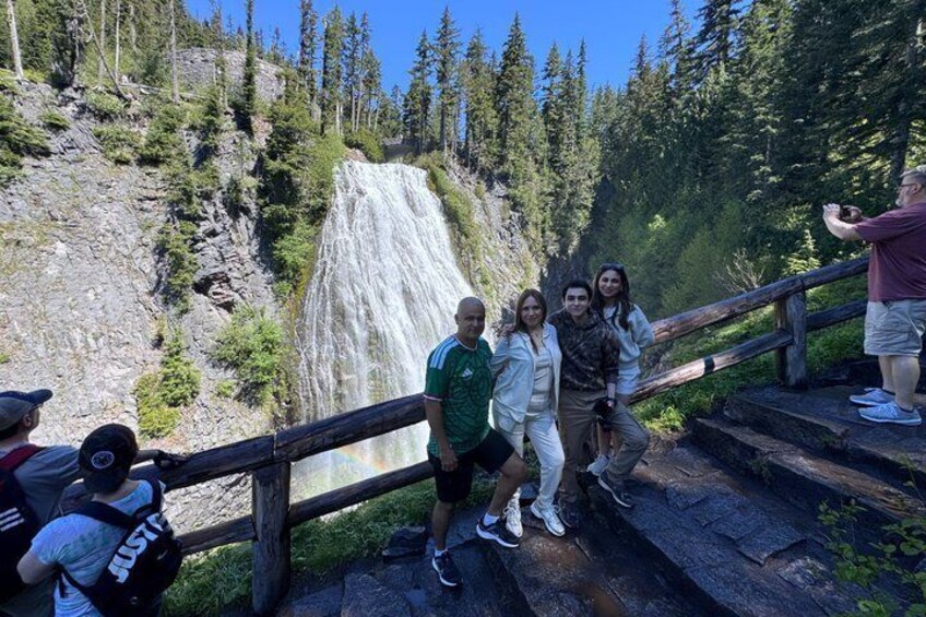 A group of people standing on a wooden staircase overlooking a waterfall. 5