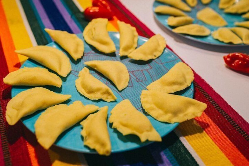 A plate of golden-brown empanadas on a blue plate with a colorful striped tablecloth. 5