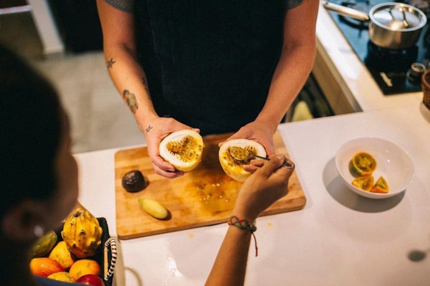 A person cutting a fruit on a wooden board, with a bowl of sliced fruit and a cutting board with a knife on a kitchen counter. 4