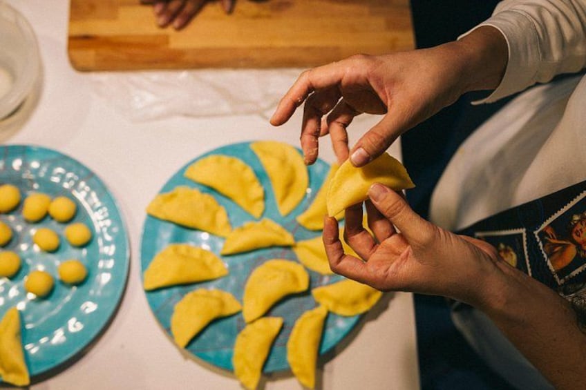 Hands preparing food, with plates of yellow and blue items on a table. 1
