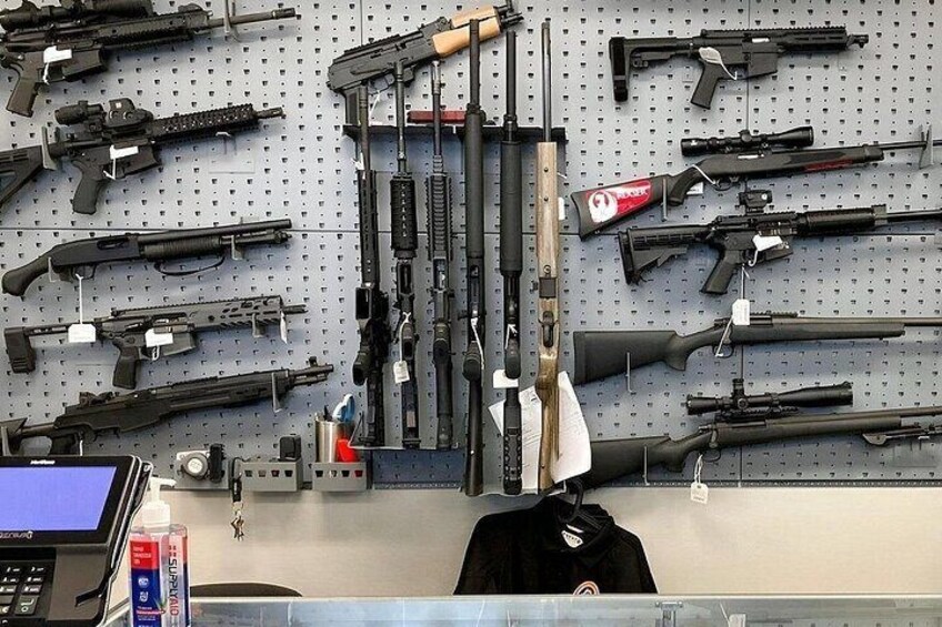 A wall of various firearms displayed on a pegboard. 4