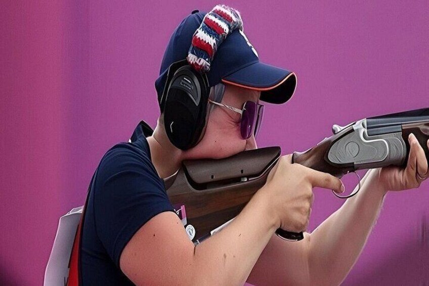 A person aiming a shotgun with a pink cap and headphones. 2