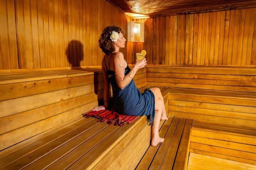 A person sitting on a wooden bench in a sauna with wooden walls and benches. 2