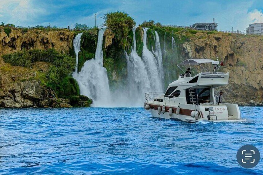 A boat named 'LINDA' on water with a waterfall in the background. 3
