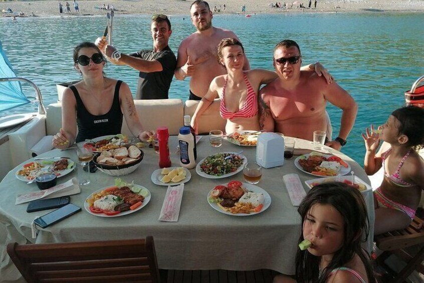 A group of people dining on a boat with various dishes on the table. 5
