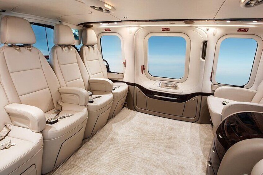 A luxurious interior with beige leather seats, a carpeted floor, and windows with a clear view. 3