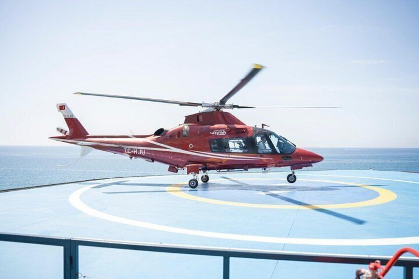 A red helicopter with the registration TC-HJY on a helipad with blue and yellow markings. 4