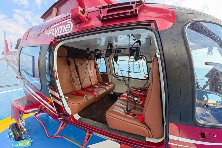 A red helicopter with 'Flyme' branding, open rear door, and interior seating. 5