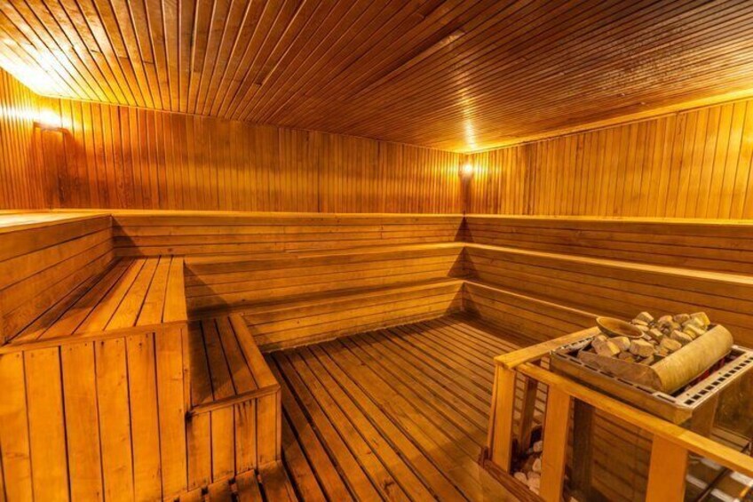 A wooden sauna with benches and a stone heating unit. 4