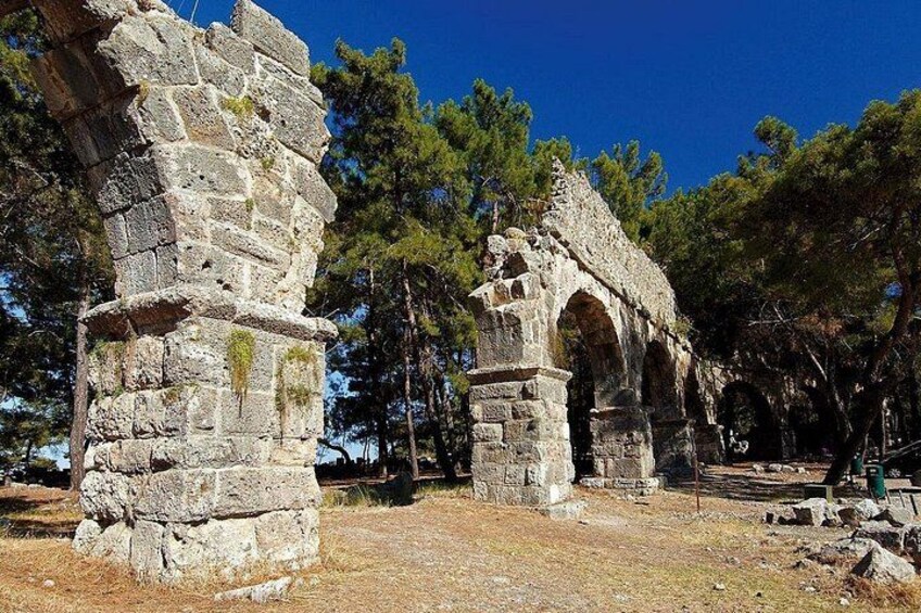 Ancient stone ruins with arches and columns, surrounded by trees. 4