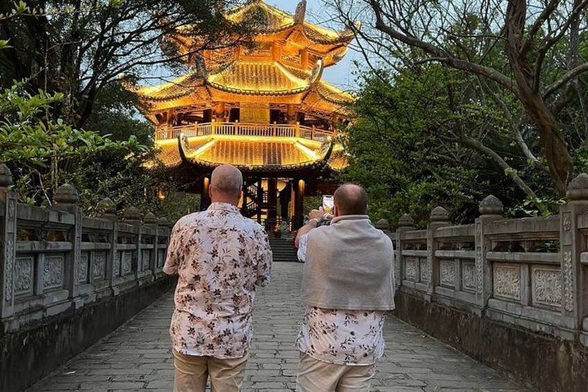 Two people walking towards a traditional Chinese pagoda with ornate golden roofs. 2
