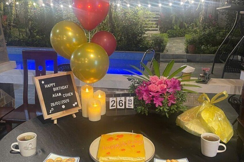 A birthday celebration setup with balloons, candles, a cake, and a sign. 2