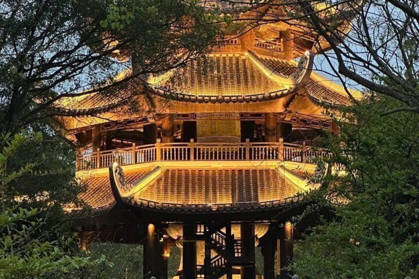 A traditional multi-tiered pagoda with ornate railings, surrounded by lush greenery. 1