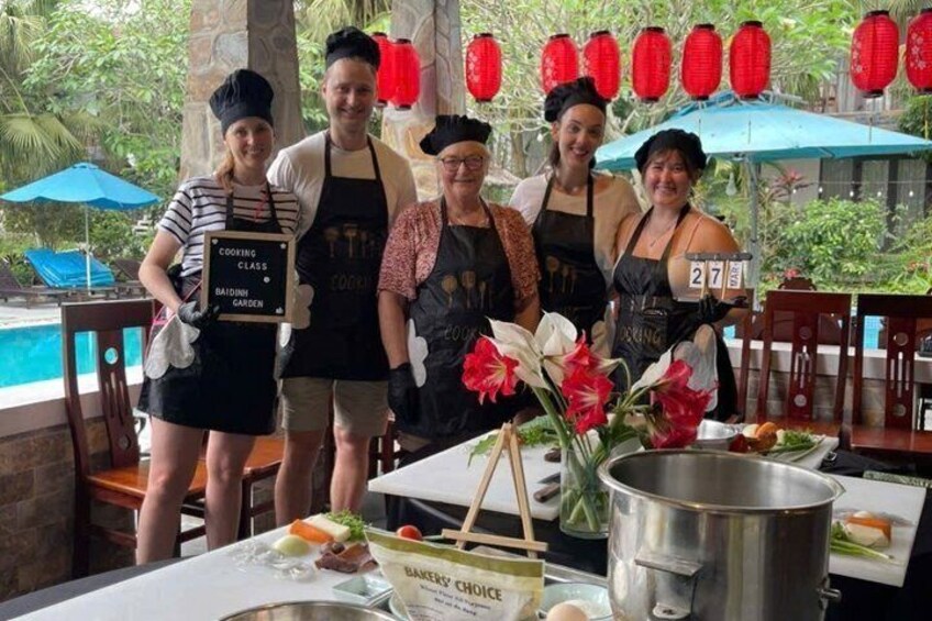 A cooking class with participants standing around a table with cooking utensils and ingredients. 3