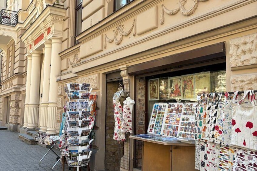 A street with a shop displaying postcards and a mannequin. 2
