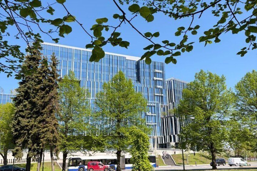 A modern glass building, trees, and a red car parked in front. 5