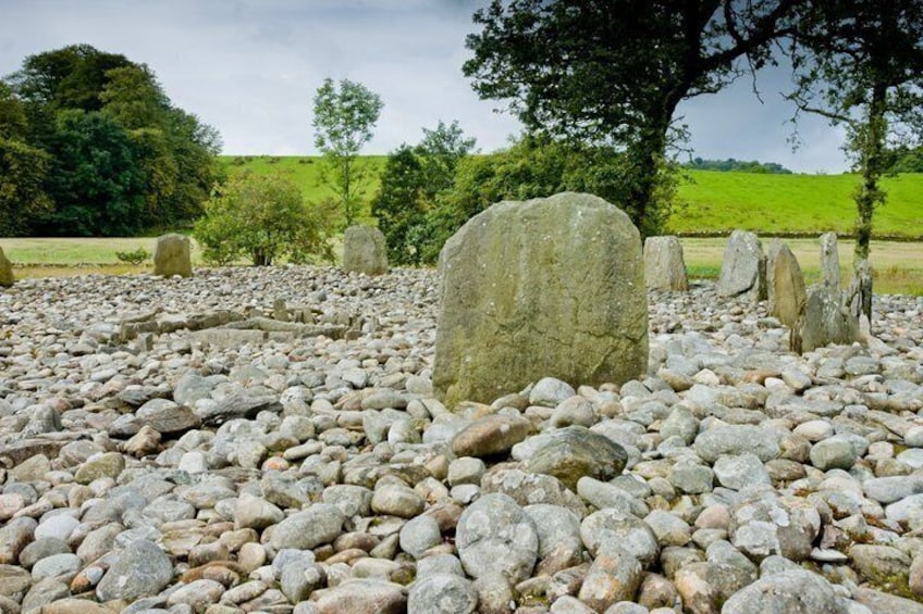 A stone circle with large upright stones in a grassy field. 3