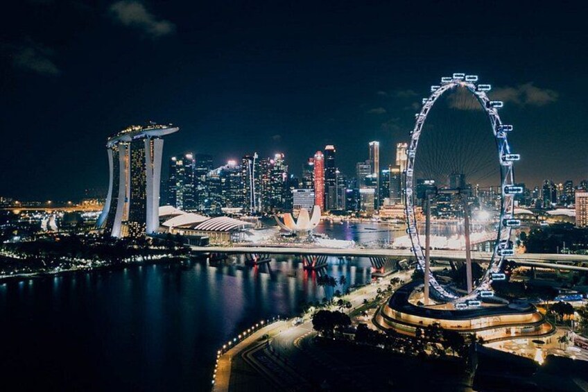 A city skyline at night with prominent buildings, including a large Ferris wheel and a distinctive tower. 2