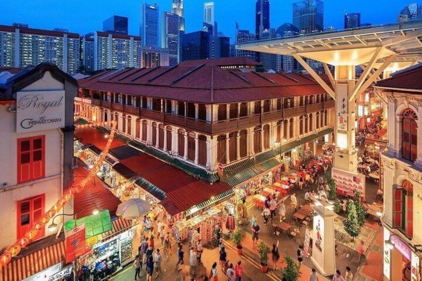 A bustling market street with historic buildings, a prominent clock tower, and a city skyline in the background. 1