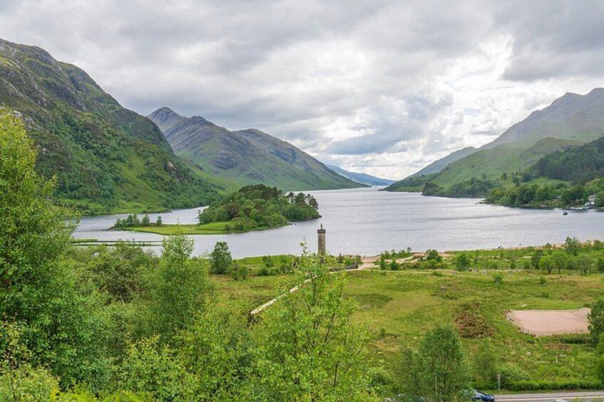 A lake surrounded by mountains, a small house, and a wooden fence. 4