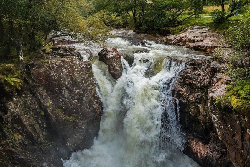 A waterfall cascading over rocks in a forested area. 2