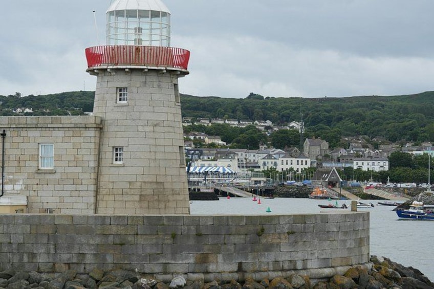 A lighthouse, a harbor with boats, and a town in the background. 2