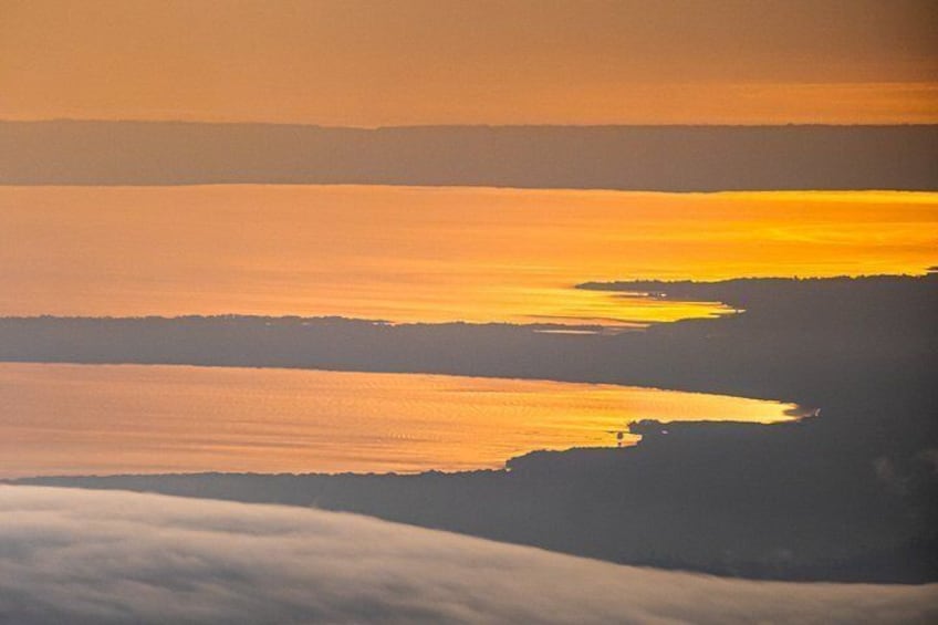 A sunset over a body of water with a coastline silhouette. 3