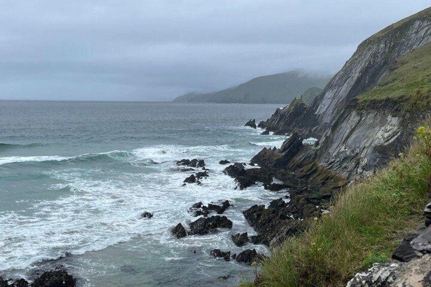 A rocky coastline with waves crashing against the shore and a cliff in the background. 2