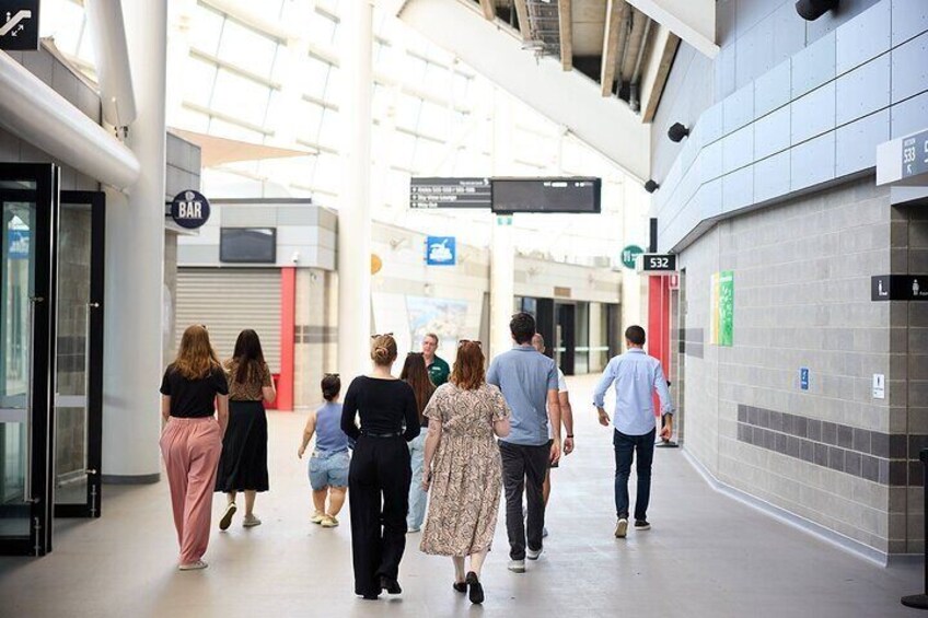 A group of people walking in a modern indoor space with a bar and directional signs. 5